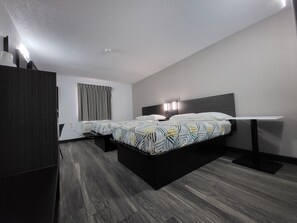A modern hotel room with a large bed, a bedside table, a wardrobe, and a window with curtains. - Motel 6 Omaha, NE (Omaha)