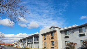 A row of modern multi-story buildings with a parking lot in front. - Motel 6 Omaha, NE (Omaha)