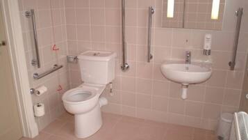 A bathroom with a toilet, a sink, and grab bars.