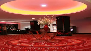 A lobby with a red carpet, a central table with a vase of flowers, and a circular design on the floor.