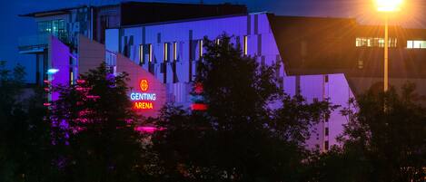 A modern building with a prominent 'Genting Arena' sign, surrounded by trees.
