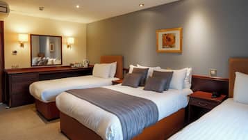 A hotel room with two beds, a dresser, a nightstand, a mirror, and a painting on the wall.