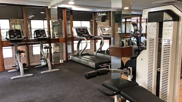 Une salle de sport équipée de tapis de course, de vélos elliptiques et de bancs de musculation.