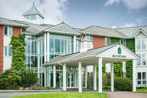A reception area with a glass entrance, a covered porch, and a brick building with a tower.