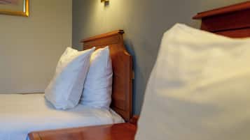 A neatly made bed with white linens and a wooden headboard.