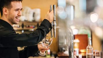 A bartender pouring a drink from a tap into a glass.