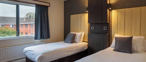 A hotel room with two beds, a large window, and a built-in wardrobe.
