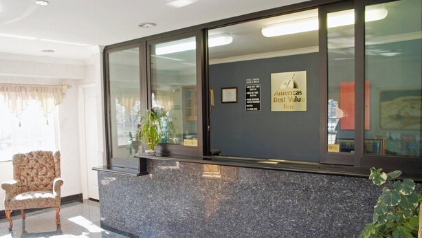 A reception desk with a framed sign, a potted plant, and a vintage chair. - The Emerald Inn on Sunset (Los Angeles)