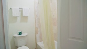 A bathroom with a toilet, a shower curtain, and a towel rack. - The Emerald Inn on Sunset (Los Angeles)