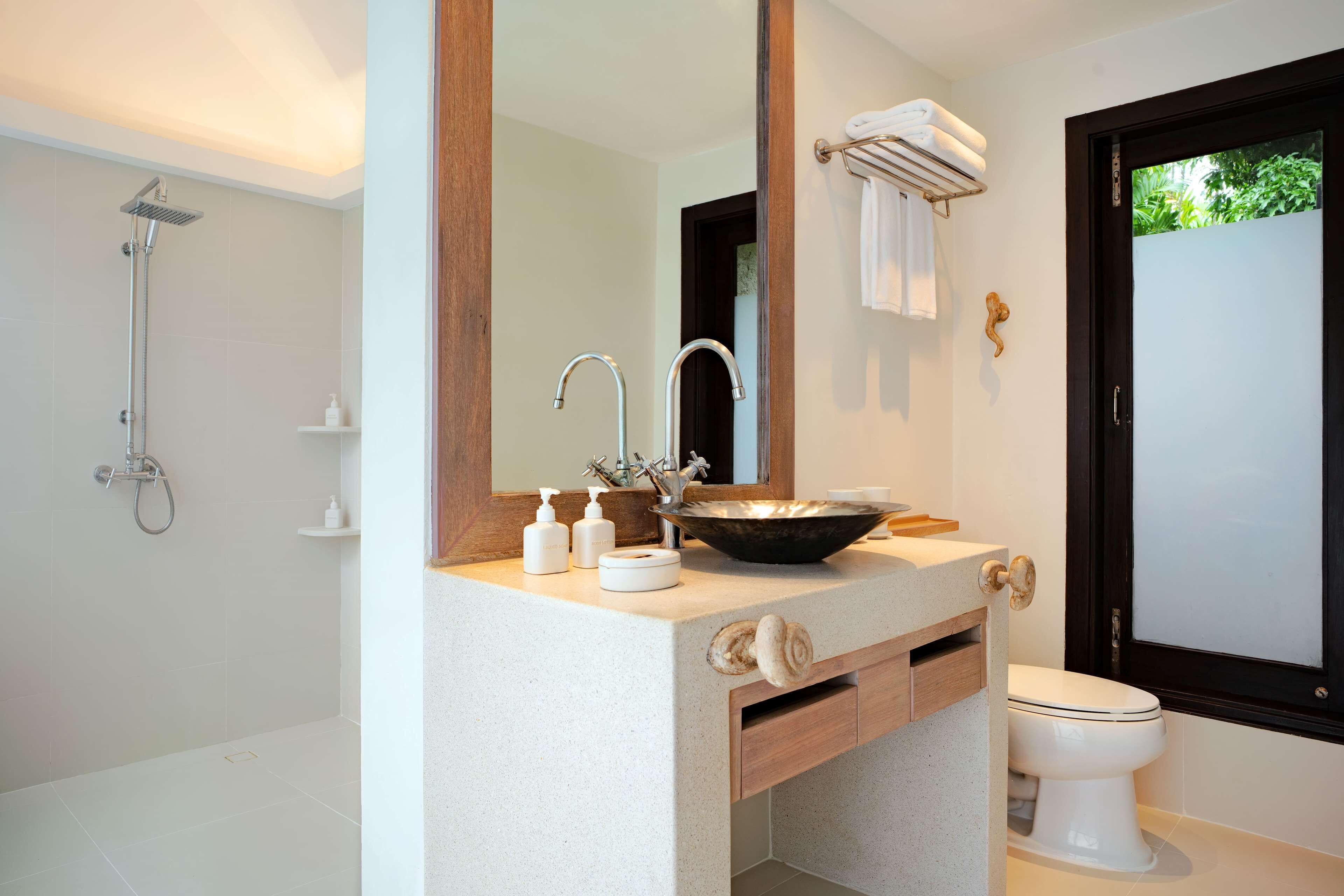 A modern bathroom with a large mirror, a sink with a bowl, a shower, and a toilet.