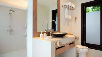 Un baño moderno con un espejo grande, un lavabo, una ducha y un inodoro.