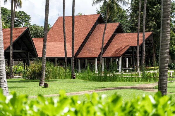 A row of bungalow-style buildings with red roofs, surrounded by lush greenery and palm trees. - Wyndham Hua Hin Pranburi Resort & Villas (Pranburi)