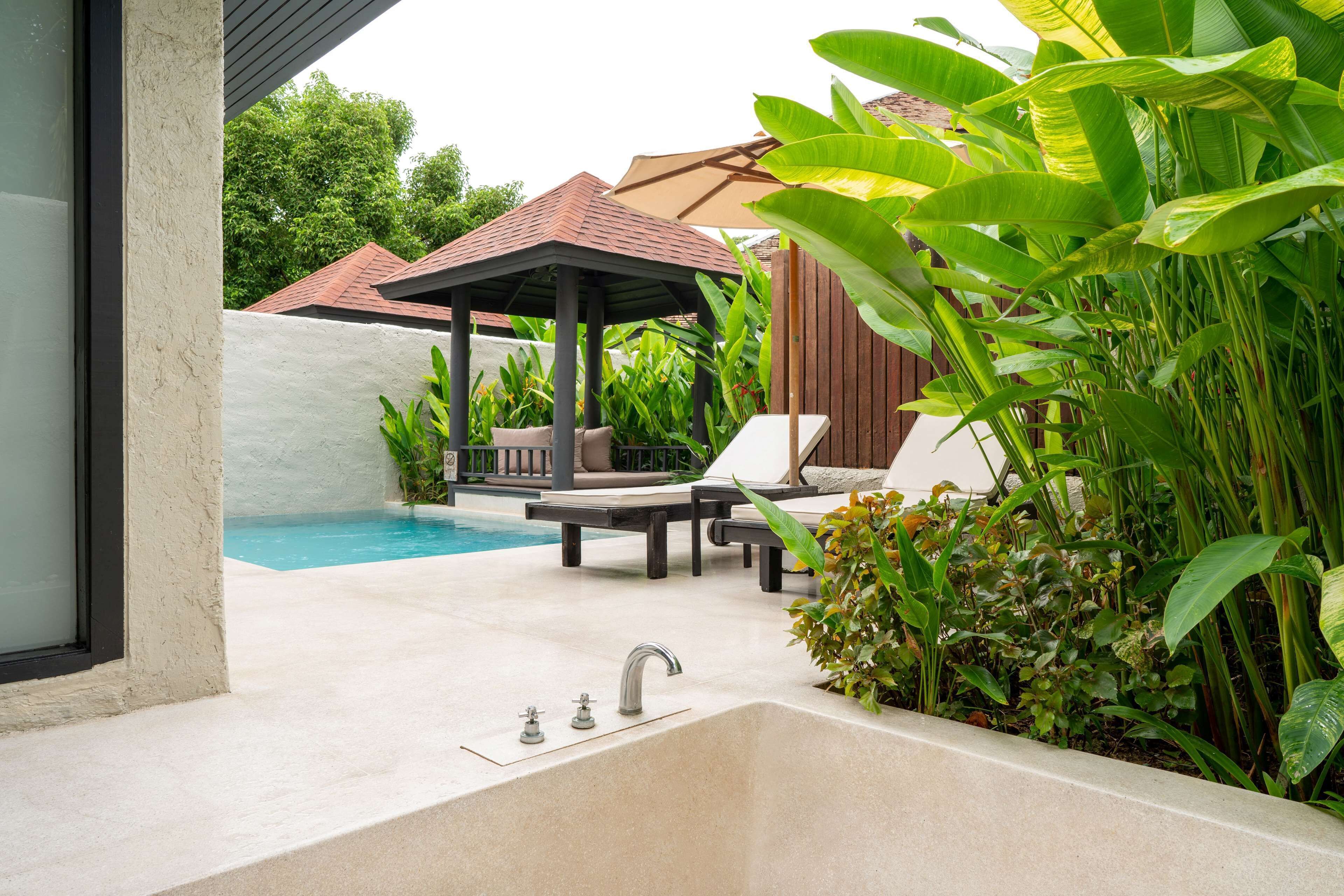 Un espace piscine doté d’un évier intégré, de chaises longues et d’un gazebo.