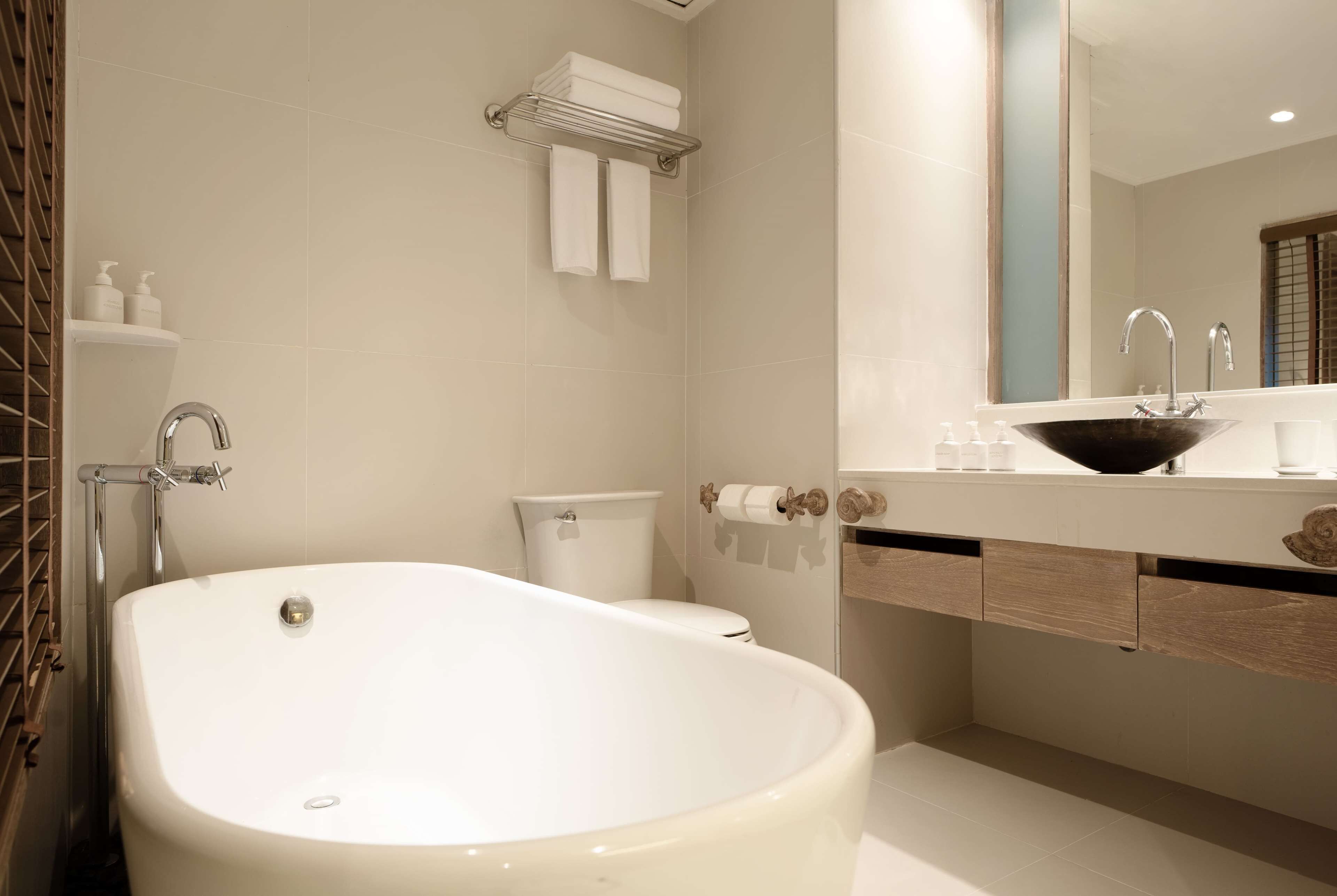 A modern bathroom with a freestanding bathtub, a toilet, and a vanity with a mirror and sink.