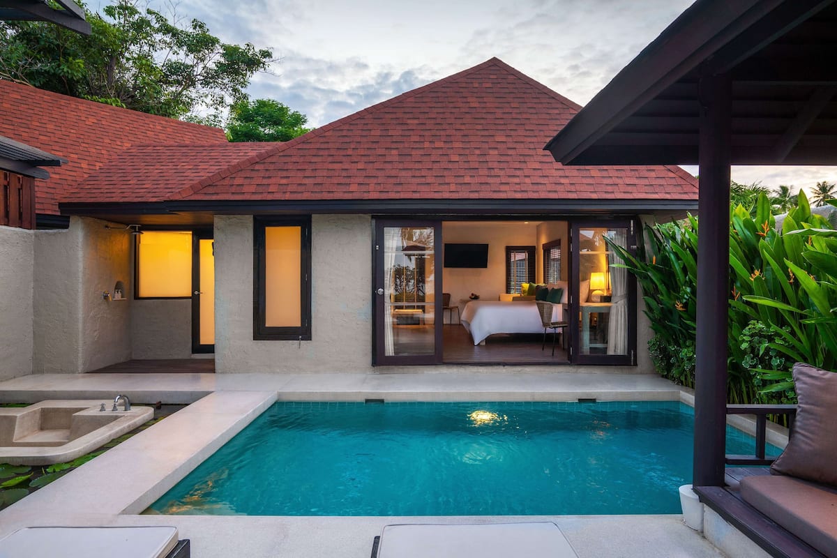 A modern villa with a swimming pool, a covered patio, and a bedroom with a view of the pool.