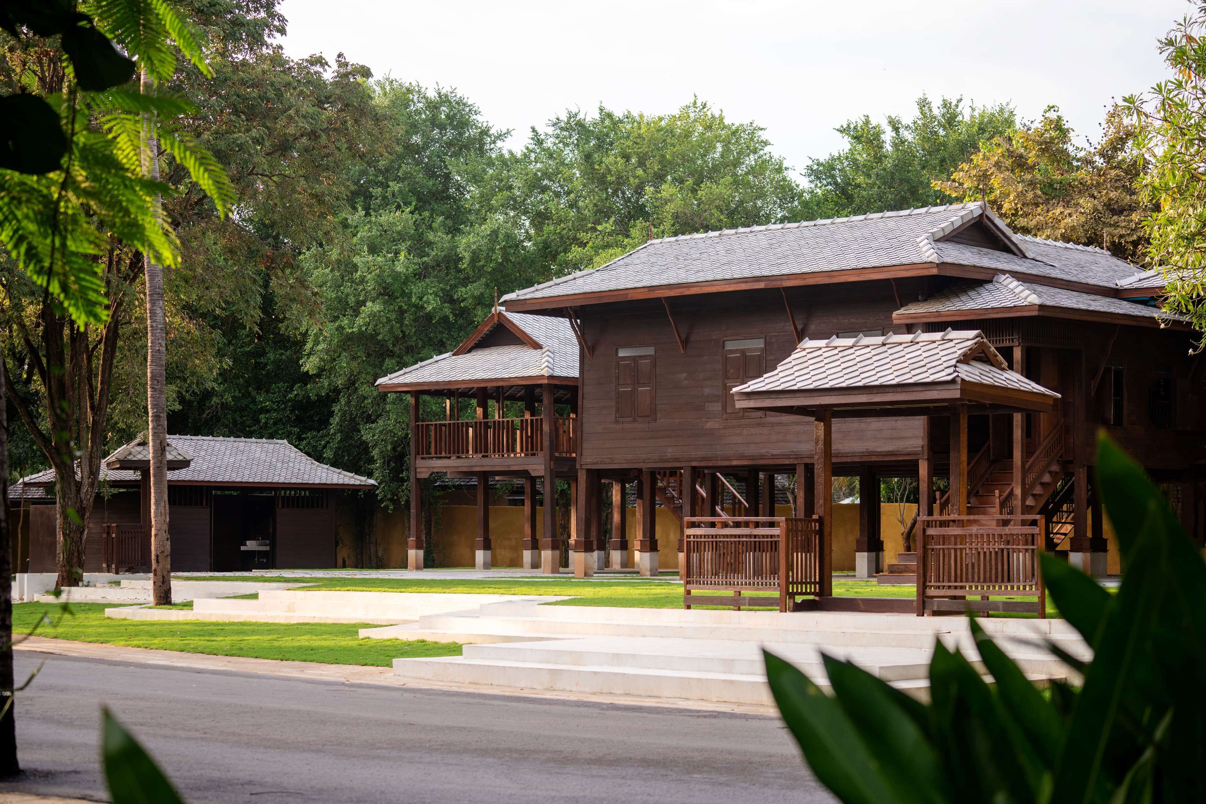 Un bâtiment traditionnel en bois, à plusieurs étages et doté de balcons, entouré d’une végétation luxuriante.