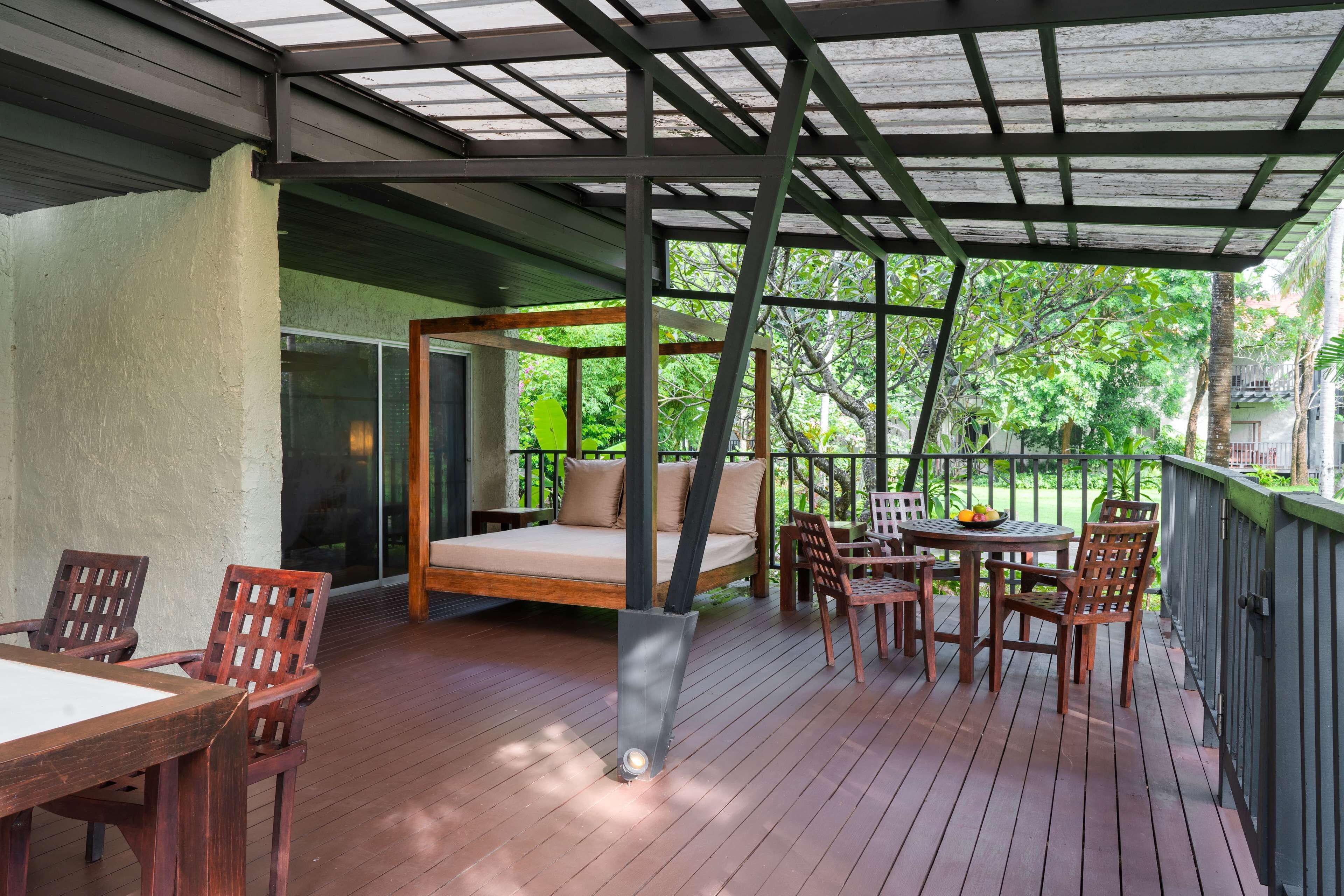 A wooden deck with a bed, chairs, and a table.