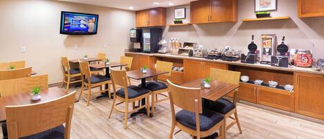 A restaurant with wooden furniture, a flat-screen TV, and various food preparation stations.