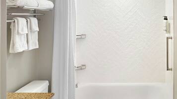 Un baño con inodoro, bañera, cortina de ducha y barra para toallas.