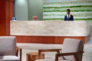 A hotel reception area with a marble counter, wooden chairs, and a decorative wall. - SpringHill Suites by Marriott Atlanta Buckhead (Atlanta)