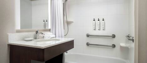 A modern bathroom with a white sink, dark wooden vanity, a bathtub, and a shower with a curtain.