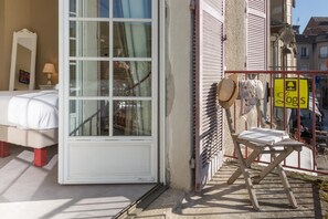 Une chambre d’hôtel avec une grande fenêtre, un lit et une petite table sur laquelle se trouvent un chapeau et une serviette.