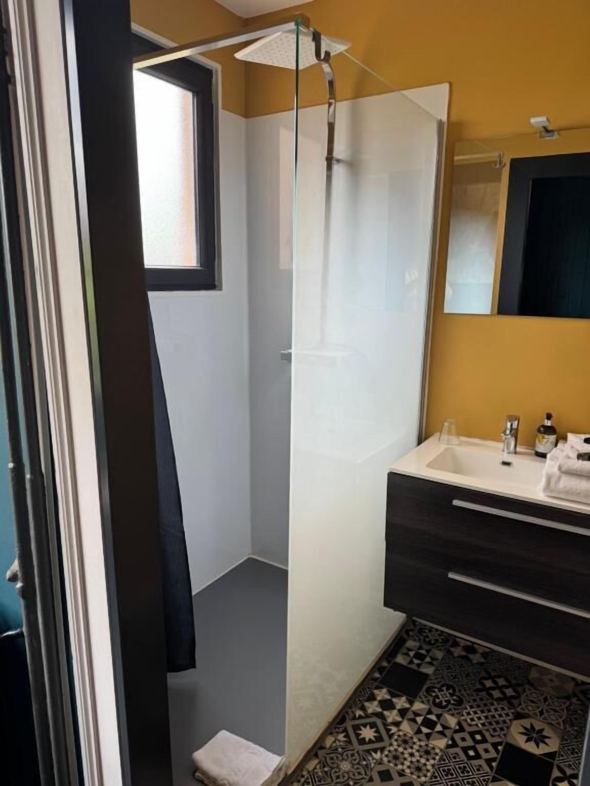 A modern bathroom with a shower, a sink, and a mirror.