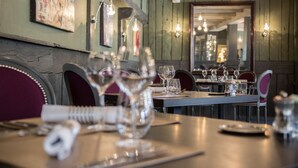 Een restaurantinterieur met houten wanden, hangende lampen en netjes opgestelde tafels met stoelen.