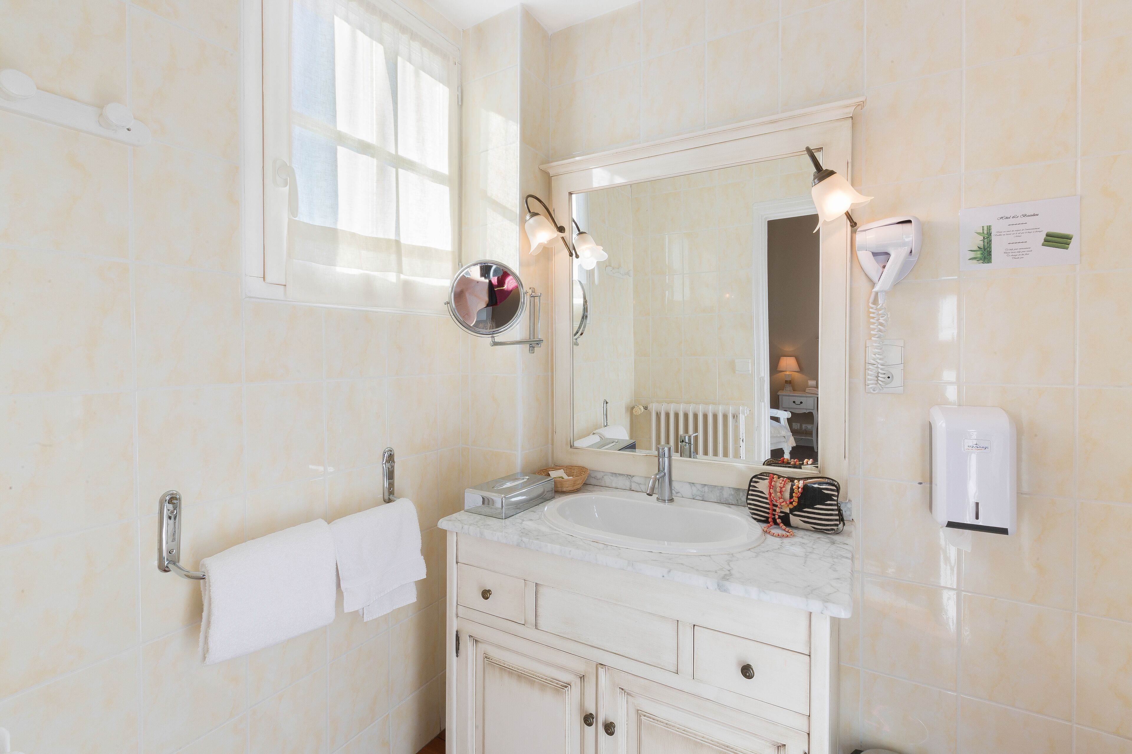 A bathroom with a large mirror, a sink, a towel rack, a hairdryer, and a hand dryer.