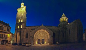 Un bâtiment historique doté d’une grande entrée en arc de cercle et d’une haute tour avec des fenêtres illuminées.