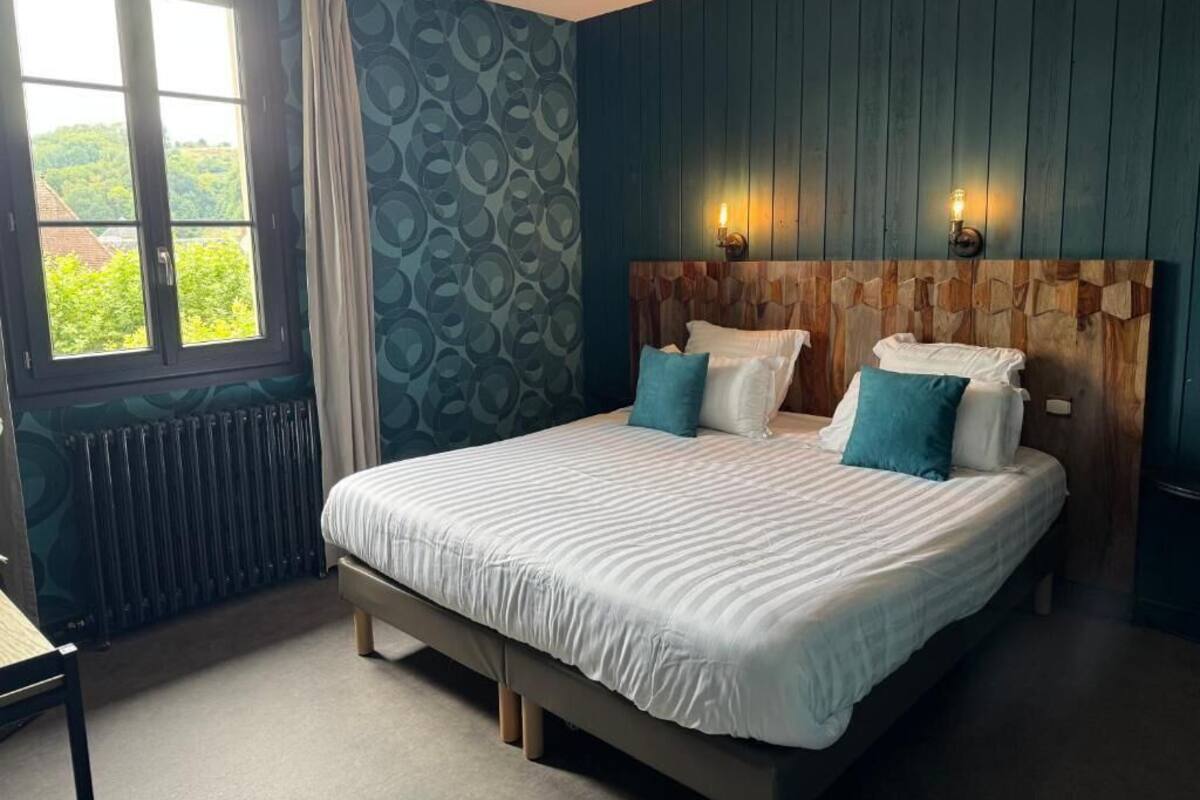 Ein Schlafzimmer mit einem großen Bett, zwei Nachttischlampen, einem Fenster mit Vorhängen und einer Heizung.