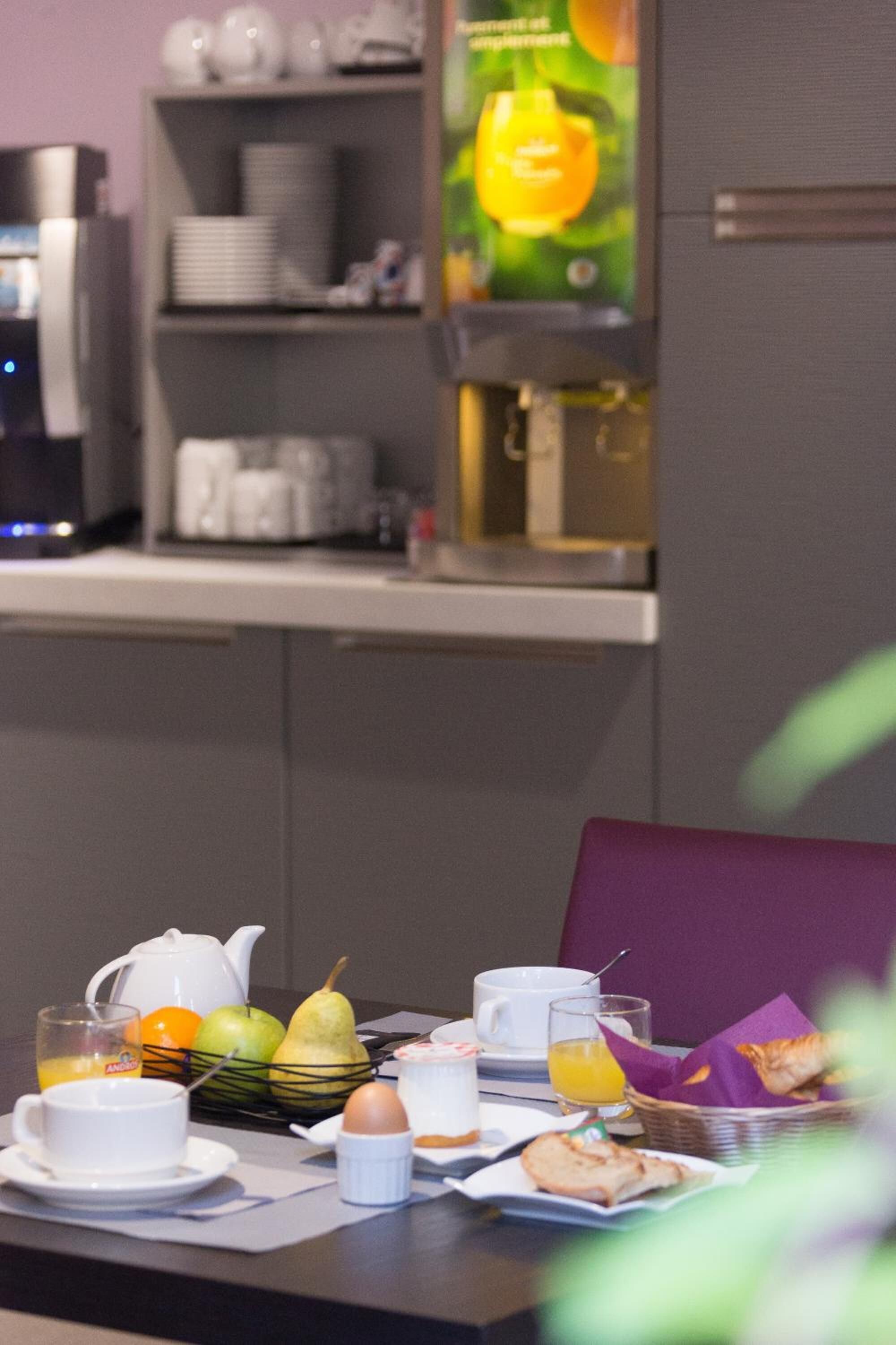 Una mesa de desayuno con tetera, fruta, huevos y pasteles.