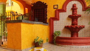 A lobby with a yellow wall, a fountain, and a reception desk.