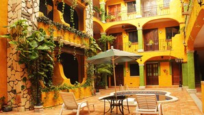 A courtyard with a pool, outdoor seating, and lush greenery.