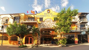 A hotel with a yellow facade, multiple balconies, and a sign reading "Hotel Hacienda del Cura".