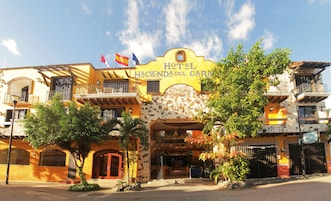 Un hotel con fachada amarilla, varios balcones y un letrero que dice "Hotel Hacienda del Cura".