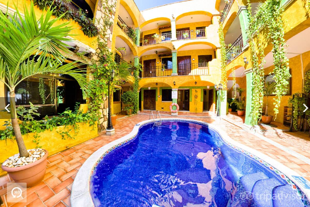 A courtyard with a swimming pool, potted plants, and a multi-story building with balconies.