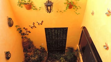A staircase with potted plants, a lantern, and a black door.