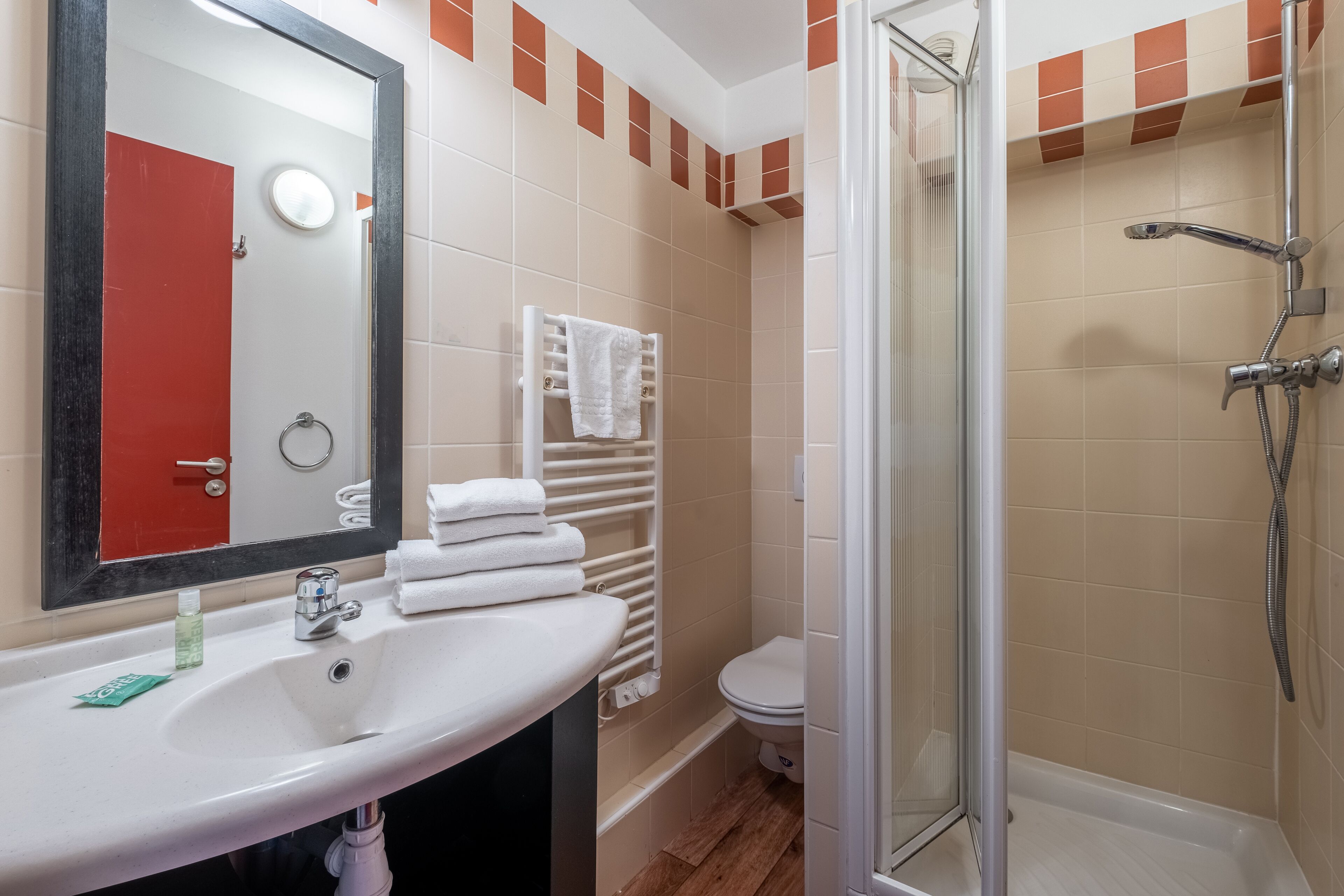 Een badkamer met een wit wastafel, spiegel, toilet en douche.