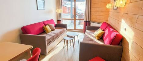 A modern interior with a wooden wall, a sofa, a small table, and a red chair.