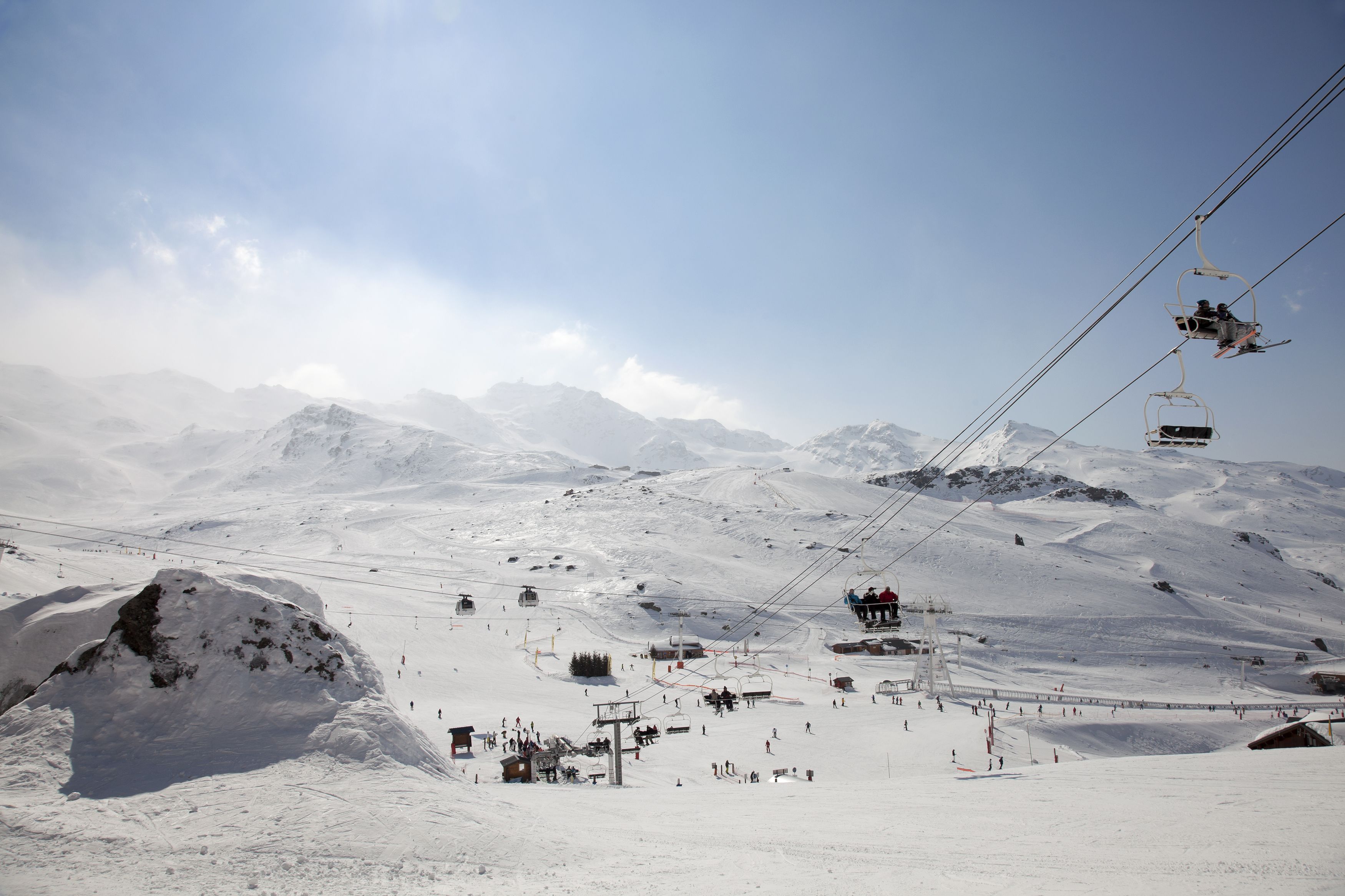 Una stazione sciistica con una seggiovia, pendii innevati e montagne sullo sfondo.