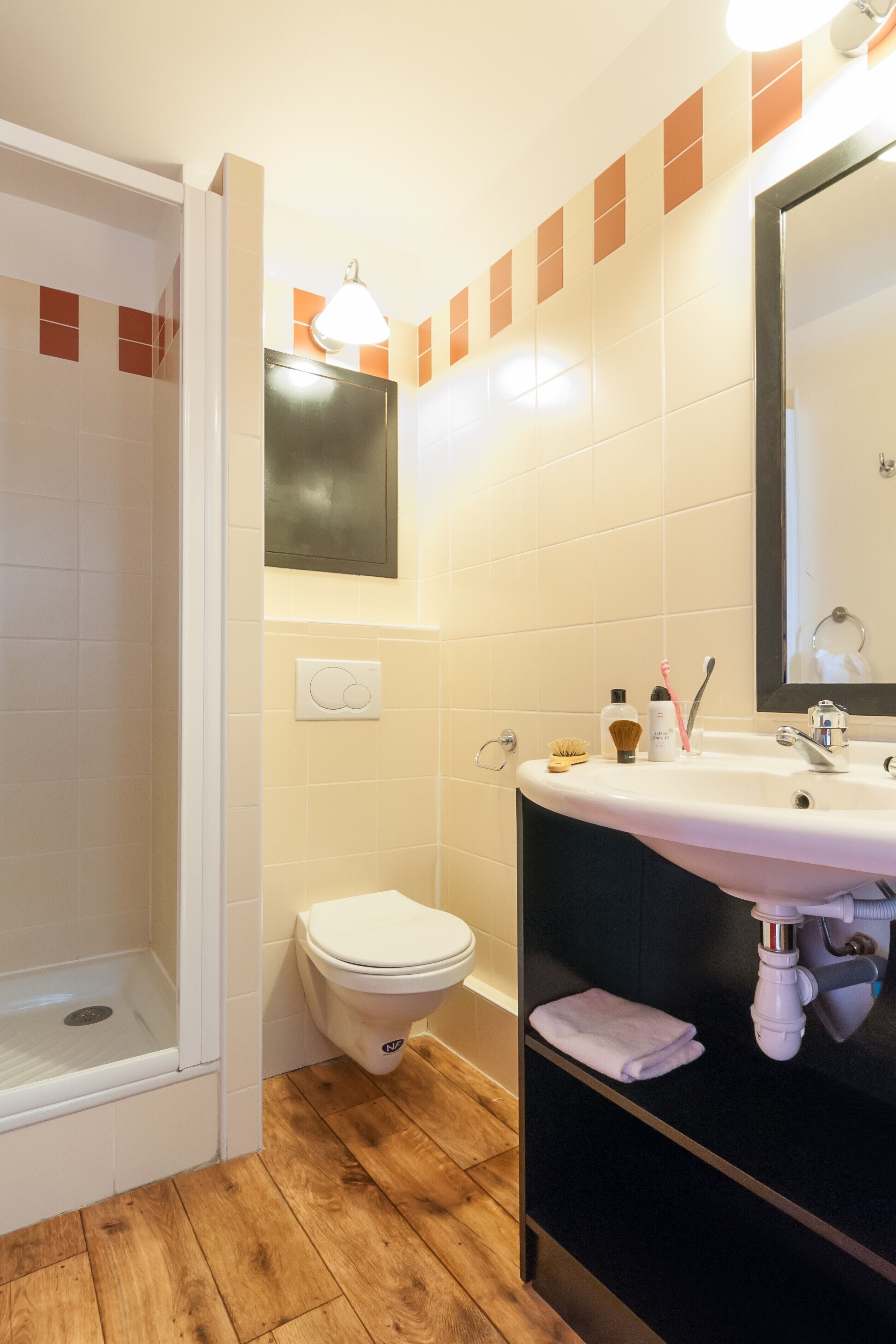 A bathroom with a shower, toilet, sink, and mirror.