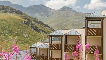 A mountain lodge with multiple rooms, each with a balcony and a view of the surrounding hills.