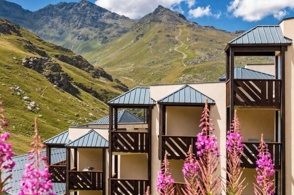 A mountain lodge with multiple rooms, a clear view of the surrounding mountains, and a path leading up the mountain. - Pierre & Vacances Résidence le Tikal (Les Belleville)