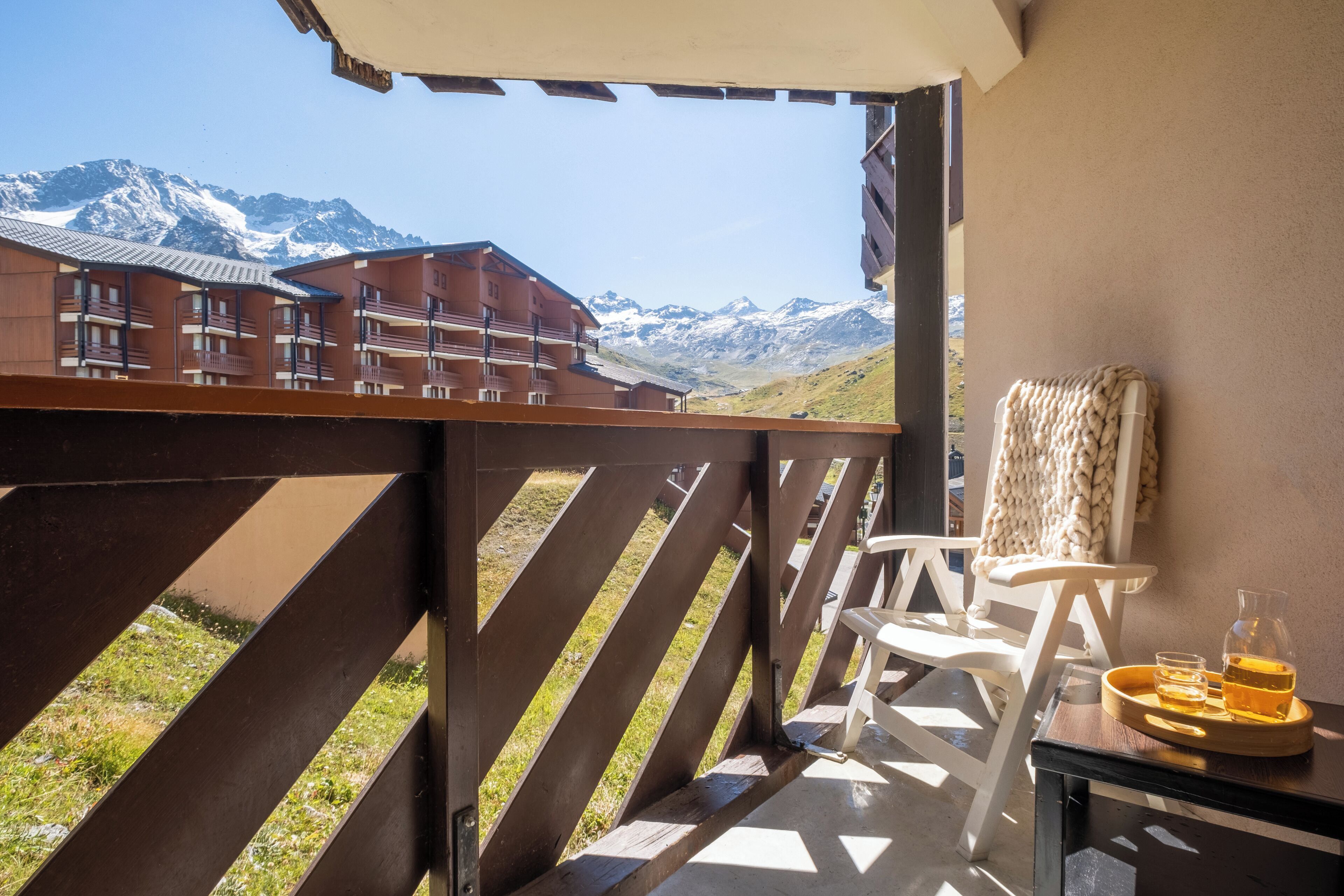 Un balcón con vistas a montañas, una silla y una bandeja con una bebida.
