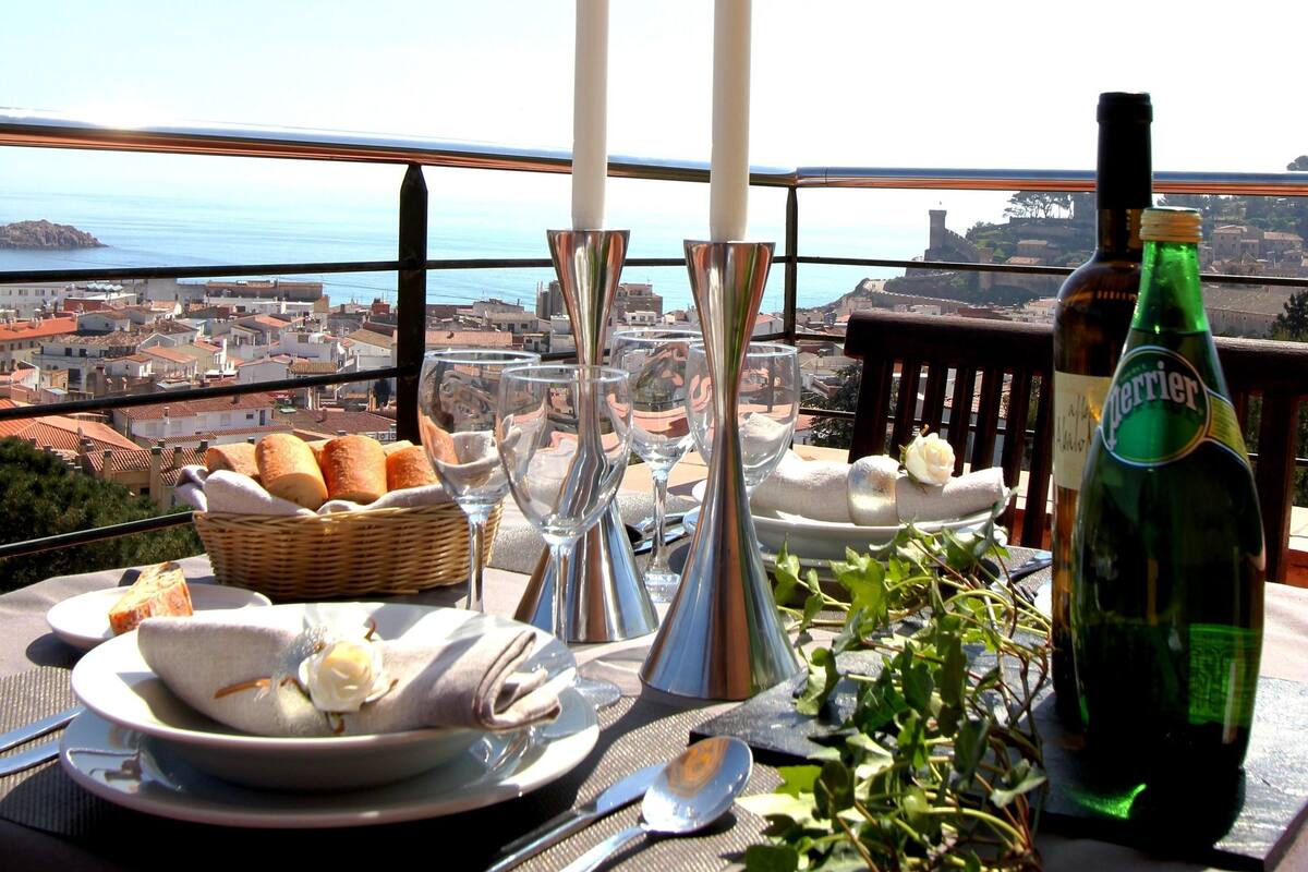 Una mesa dispuesta para una comida con vistas a una ciudad costera.
