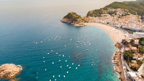 Une vue aérienne d’une ville côtière avec une plage, des bateaux et des bâtiments.