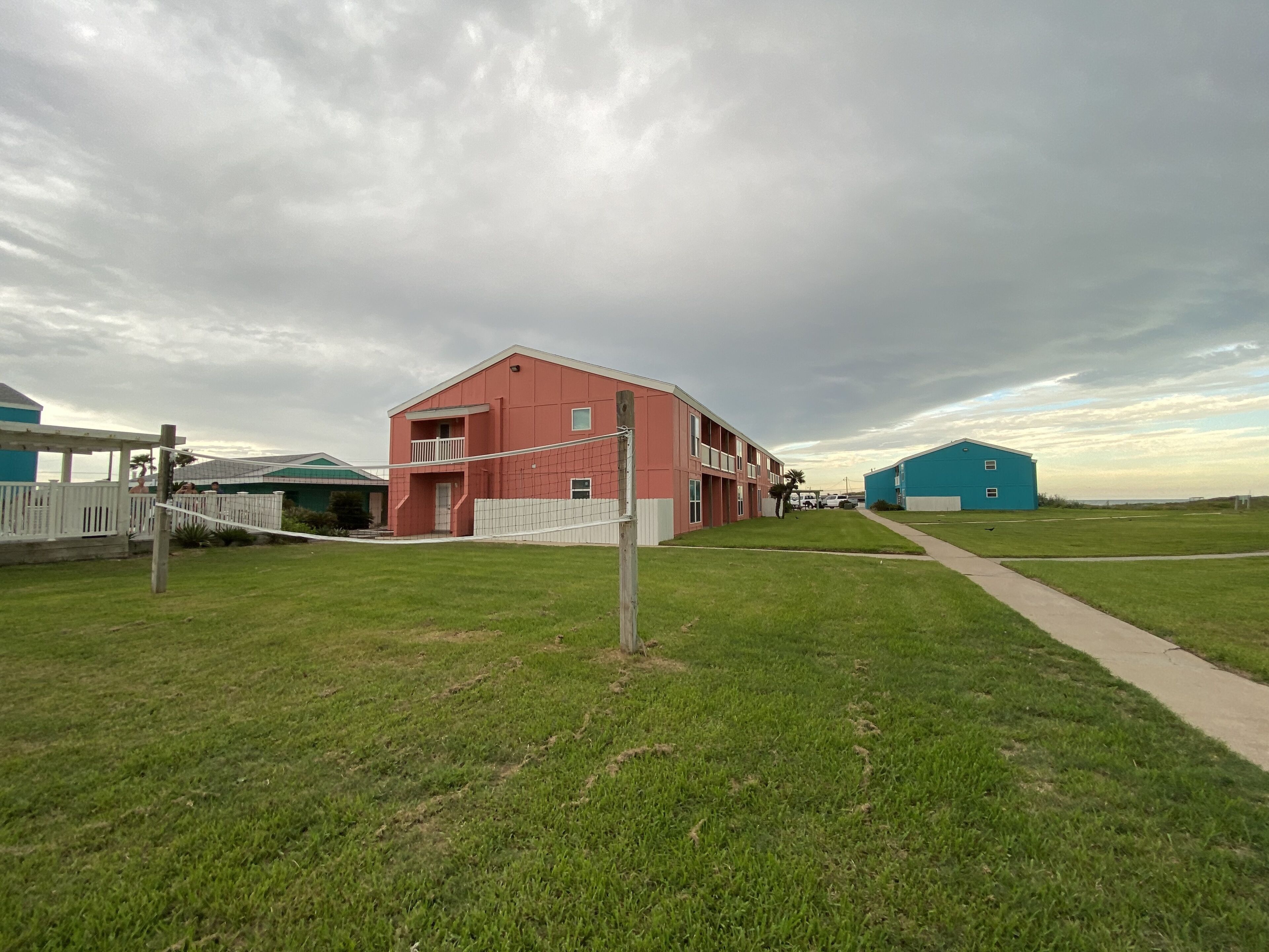 A residential area with a red building, a blue barn, and a white fence.