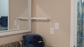 Un baño con lavabo, espejo, toallero y un inodoro visible a través de una puerta abierta.