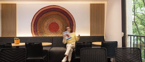 Un interior moderno con un sofá, sillas tejidas negras, una mesa de madera y una gran obra de arte circular en la pared.